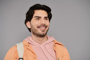 Young handsome man smiling with joy against a gray backdrop during a casual urban outing