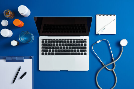 Doctor desk table with stethoscope, water, pills with laptop