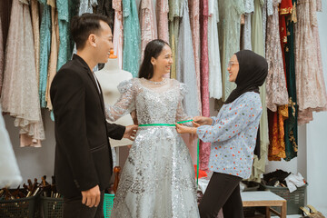 A skilled tailor is fitting a brides exquisite dress in a vibrant boutique full of fashion