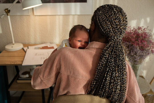 Mother lulling newborn while working
