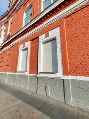 A red brick building with closed white automatic shutters on its windows, emphasizing security and safety. The image highlights modern protection solutions on classic architecture.