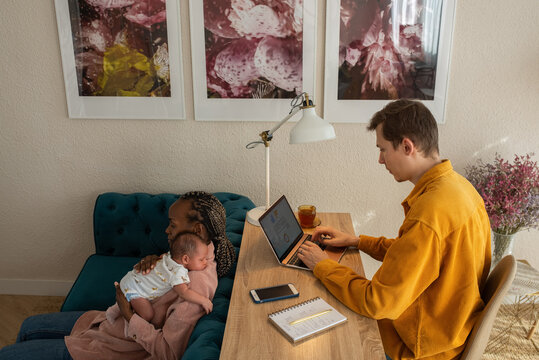 Focused man working at home next to his wife and baby