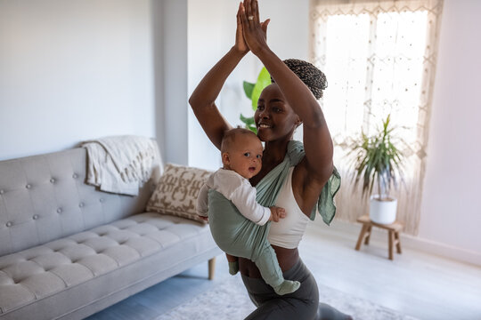 Young woman exercising with baby in sling