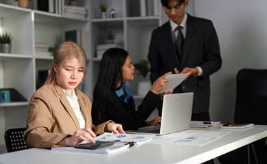 Diverse Business Team Collaborating on Work Plans in Modern Office Setting with Laptops and Documents