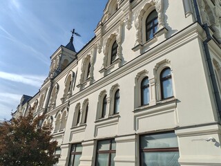 A historic building with ornate arched windows and intricate decorative elements, set against a clear blue sky. The elegant design reflects classical architectural sophistication.