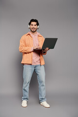Young man working on laptop with headphones, showcasing style and creativity in modern workspace
