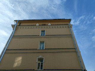 A beige building with minimal ornamentation, featuring evenly spaced rectangular windows and clean horizontal lines. The facade shows a mix of simplicity and modern functional design.