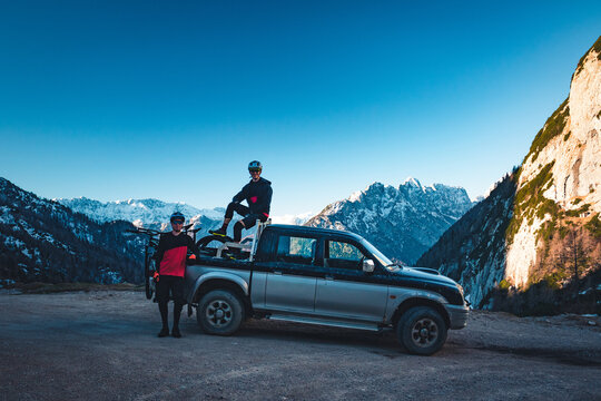 Two riders with pickup truck and mountains on background.
