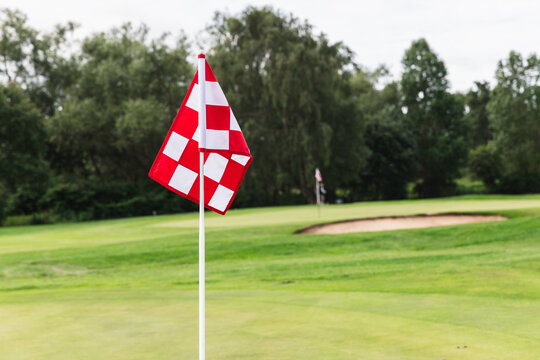 Red Flag Marking Golf Hole on Golf Field