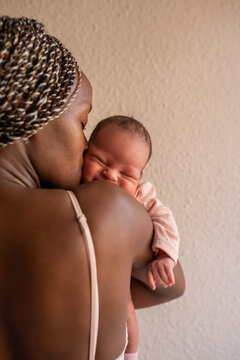 Mother kissing smiling newborn