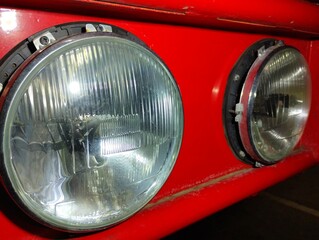 Round car headlights on the body of a red truck. © Олег Струс
