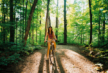 Woman riding bicycle in the forest in summer 