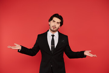 Confident young man expressing curiosity against a vibrant red background