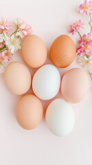 Pastel colored eggs with pink and white flowers on light background