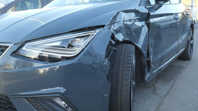 A car with front side damage from a collision, parked on street.