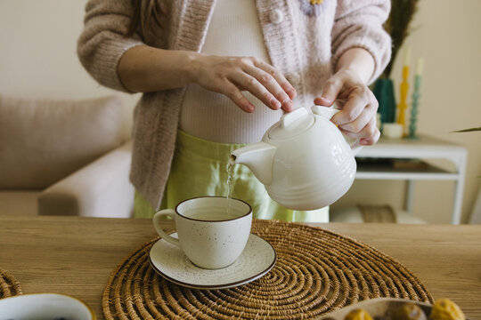 Pregnant woman pouring tea into a cup