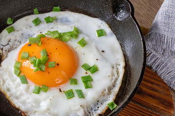 Fried egg with green onions in a cast iron skillet, top view,close up