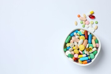 Various pills in a bowl on white background