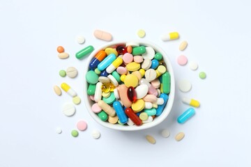 Various pills in a bowl on white background