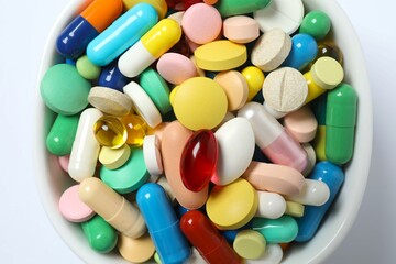 Various pills in a bowl on white background