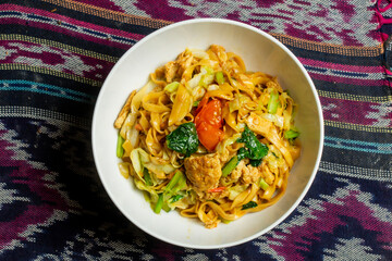 Thai Drunken Noodles Recipe, Drunken Noodles is a typical Thai dish with Rice Noodles. Typical Thai food on a traditional cloth tablecloth