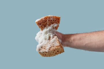 Close up of strong male hand squeezing foamy brown sponge