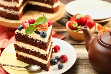 Piece of delicious chocolate sponge cake with berries served on wooden table, closeup