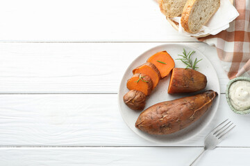 Tasty cooked sweet potatoes served with rosemary and sauce on white wooden table, top view. Space for text