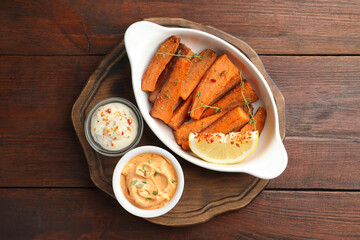 Pieces of tasty cooked sweet potato in baking dish served on wooden table, top view