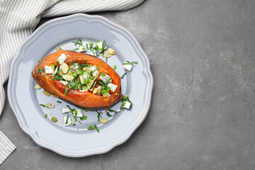 Tasty cooked sweet potato with feta cheese, pumpkin seeds and green onion on grey table, top view. Space for text