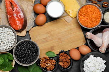 Different fresh products rich in estrogen and wooden board on grey textured table, flat lay