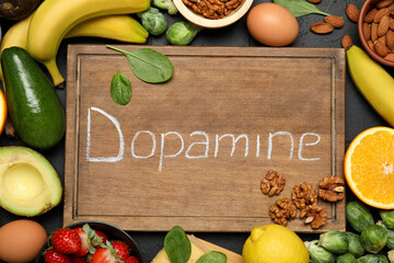 Wooden board with word Dopamine and different fresh products on grey table, flat lay