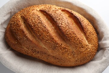 Freshly baked bread with seeds in basket on white background, above view