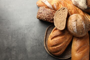 Different freshly baked bread loafs on grey table, flat lay. Space for text