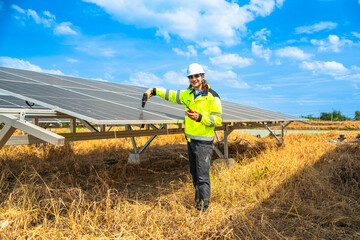 An engineer wearing safety gear inspects a large solar panel using a power drill under a vibrant...