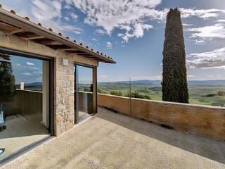 Modern villa overlooking rolling hills of tuscany with cypress tree