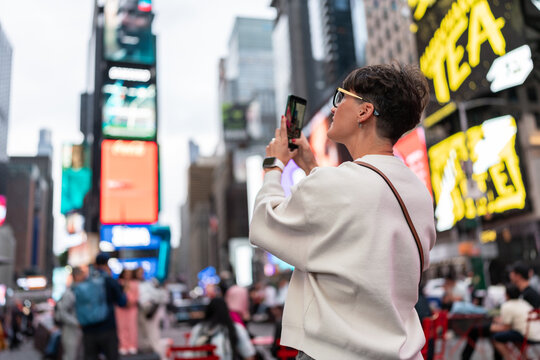 Tourist taking photos of times square billboards in new york city