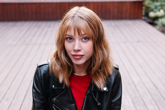 Young woman in stylish leather jacket poses confidently outdoor