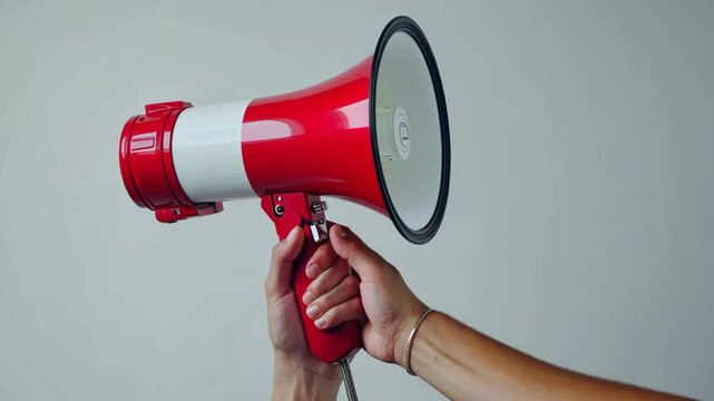 Red megaphone held by a hand during an announcement in a public space at daytime