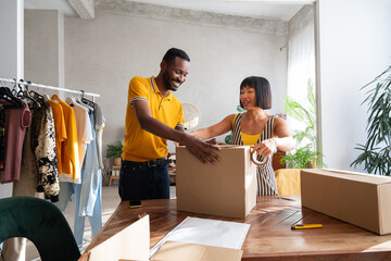 Couple Preparing Boxes For Delivery Of Their Old Clothes To Buyers