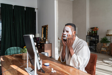 Man Applying Cosmetic Face Mask At Living Room