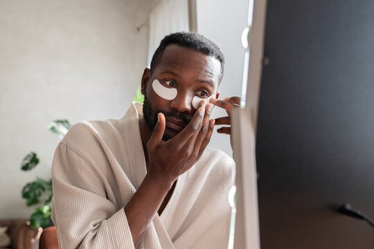 Black Man Applying Eye Patches Indoors