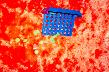 Colourful strategic connect four game play on a red furry background