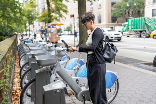 Businesswoman using smartphone to rent electric bike in new york city
