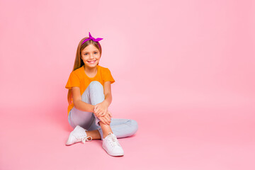 Portrait of her she nice attractive lovely cheerful cheery confident glad pre-teen girl wearing yellow t-shirt sitting on floor isolated over pink pastel background