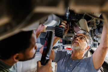 Male engineers repairing motor vehicle at garage