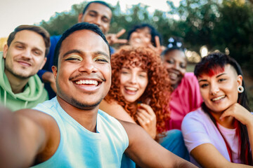 Young diverse people smiling at mobile phone camera at city park. African nonbinary taking selfie...