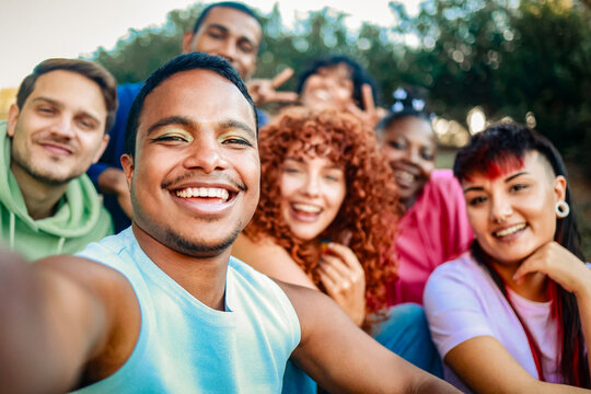 Young diverse people smiling at mobile phone camera at city park. African nonbinary taking selfie with friends. LGBT community - Powered by Adobe