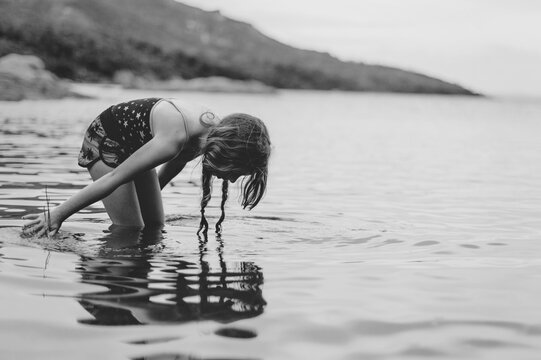 Tween girl playing alone in the water of Coles Bay in Tasmania