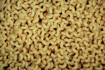 raw pasta in the shape of twisted horns (Stortelli) scattered on the surface ready for cooking